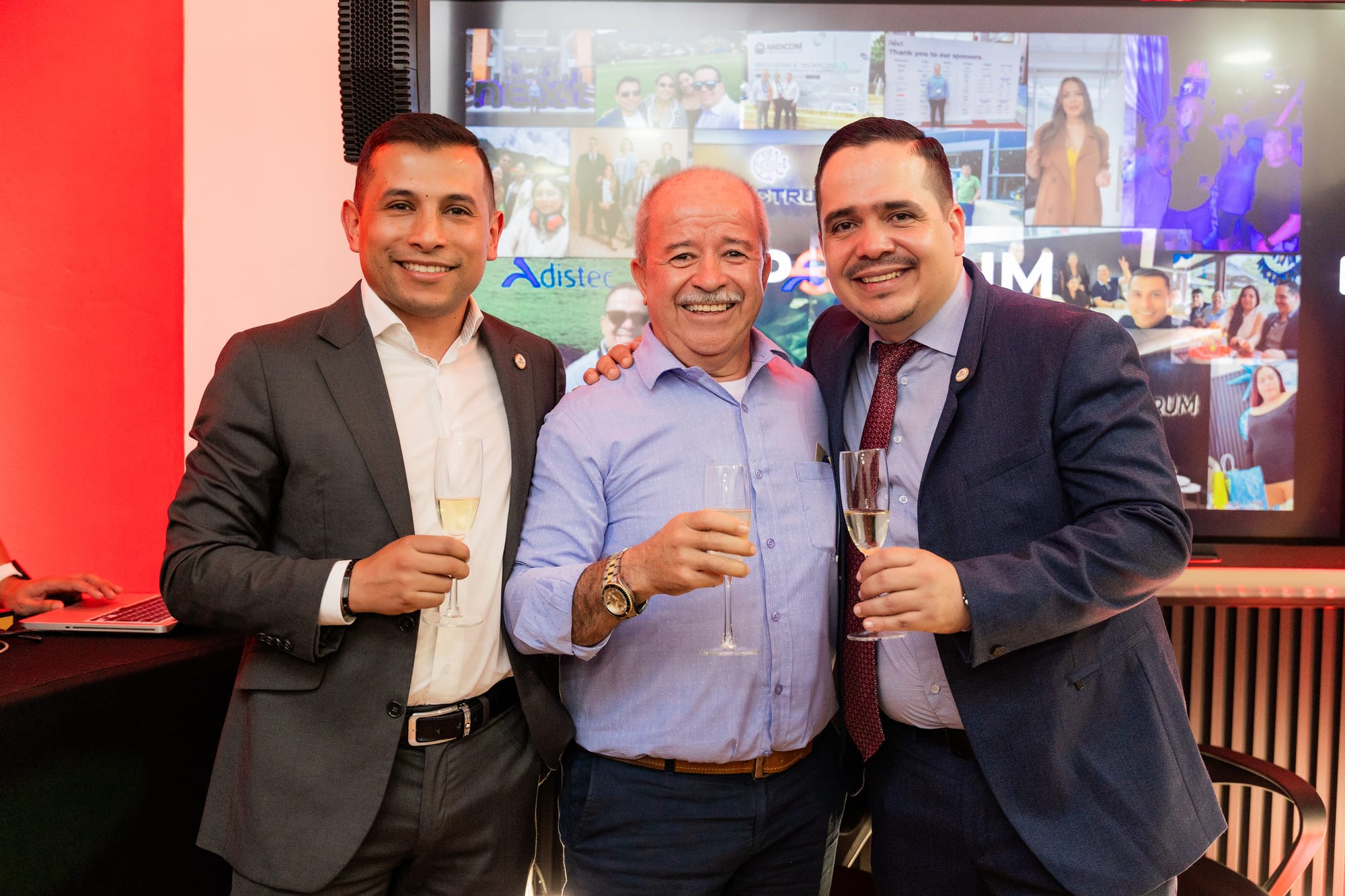 Tres personas sonríen y levantan sus copas para brindar durante la celebración